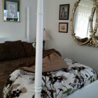 A cozy bedroom with a four-poster bed and an ornate mirror on the wall.