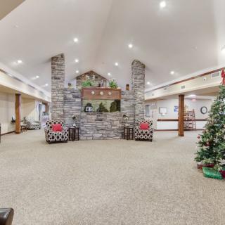 A cozy lobby with holiday decorations, featuring a stone fireplace and Christmas tree.