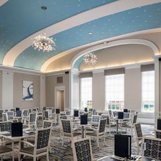 An elegant and modern conference room with a blue arched ceiling and chandeliers, set up for a professional meeting.