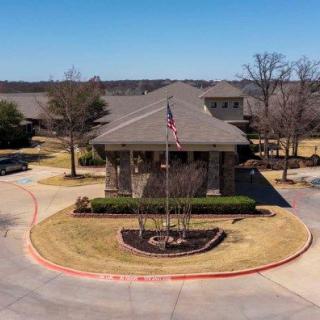 A suburban building with a flagpole in the roundabout on a sunny day.