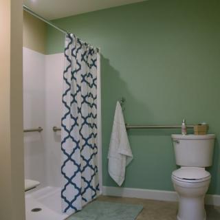 A neatly organized bathroom with a green wall and a shower area.