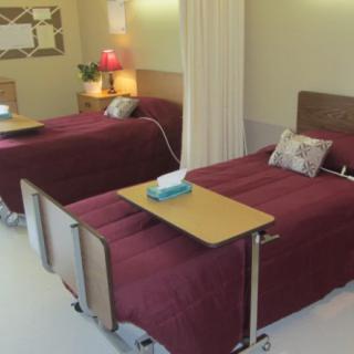 A healthcare facility room with two beds separated by a privacy curtain.