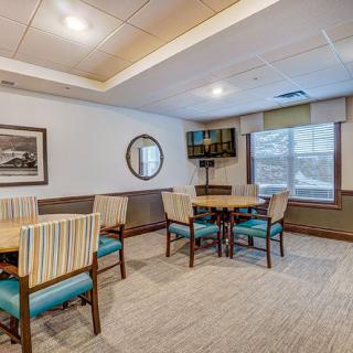 A cozy dining area with tables and chairs, featuring wall art and a large window.
