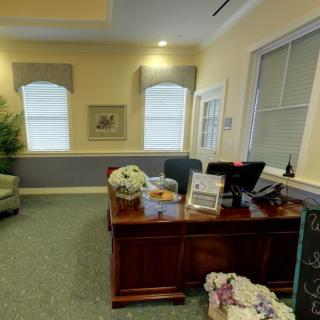 A well-decorated office space with a wooden desk, computer, and natural light from the windows.
