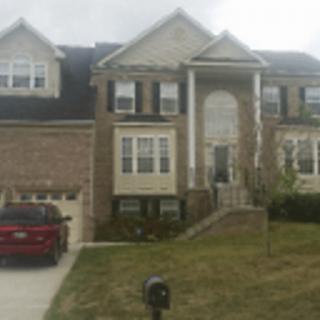 A two-story suburban house with a brick exterior and a car parked in the driveway.