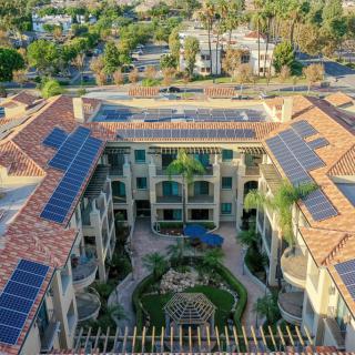 Aerial view of a building complex with solar panels on the rooftop and a central courtyard.