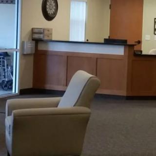 An empty waiting room with a reception desk and chair.