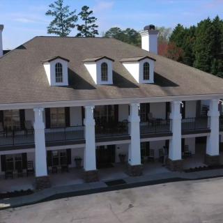 A two-story building with prominent columns and a large roof, featuring balconies on the upper floor.