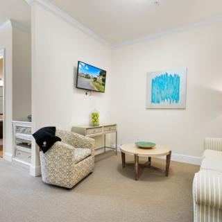 A modern and minimalist living room with neutral tones, featuring comfortable seating, a coffee table, and colorful wall art.