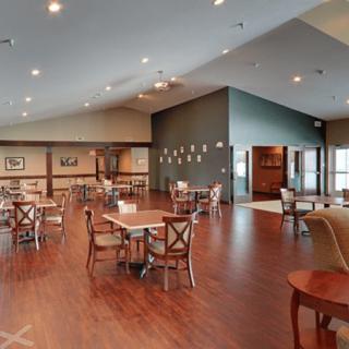 An empty dining area with wooden floors and neatly arranged tables and chairs.