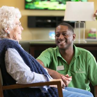 A caregiver happily interacting with an elderly person in a supportive environment.