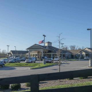 A building with a parking lot and several cars under a clear blue sky.