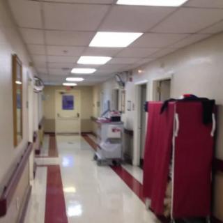A hospital hallway with medical equipment and a clear, polished floor.