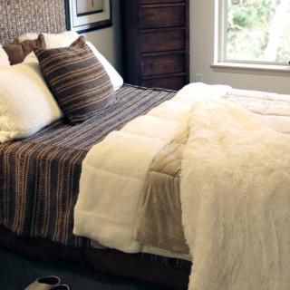 A cozy bedroom with a neatly made bed featuring striped pillows and a plush blanket.