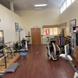 A spacious gym area equipped with various exercise machines and rehabilitation tools.
