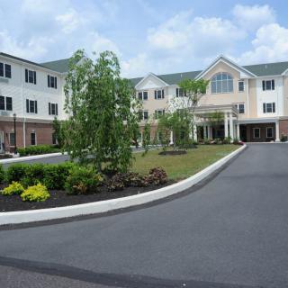 A modern residential building with well-maintained landscaping and a curved driveway.