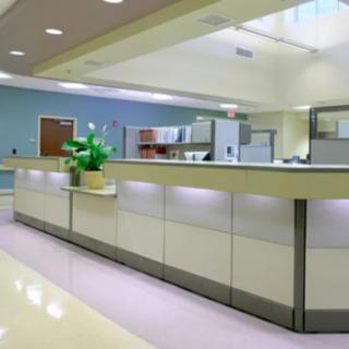 Modern hospital reception area with a sleek desk and indoor lighting.