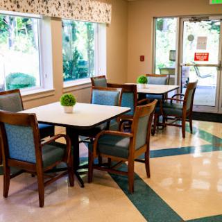 A cozy dining area with tables and chairs, illuminated by natural light.