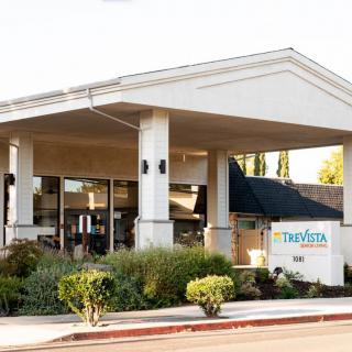 An entrance to a building with a landscaped area and a sign.