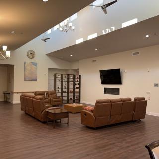 A cozy living room featuring a set of brown leather sofas, a television mounted on the wall, and a bookshelf in the corner.