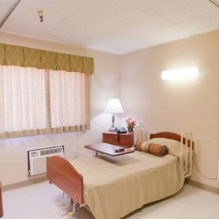 A clean and minimalistic hospital room with a single bed and a lamp.