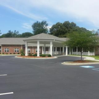 A medical facility with a circular driveway and surrounding trees.