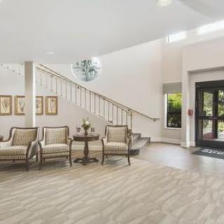 A spacious lobby featuring a seating area with elegant chairs, a staircase, and an entrance door.