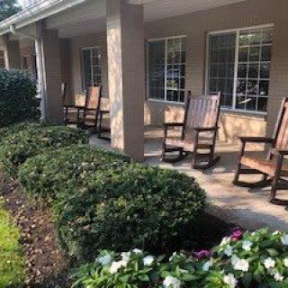 A cozy porch with wooden rocking chairs overlooking a well-maintained garden.