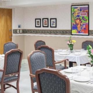 A dining area with set tables, decorated with flowers and colorful artwork on the wall.