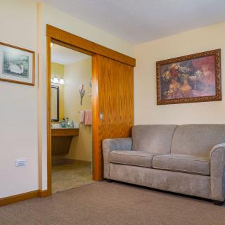 A cozy living room with a sofa and artwork, opening into a bathroom.