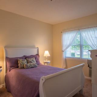 A cozy bedroom with purple bedding and warm lighting.