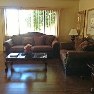 A cozy living room featuring comfortable couches and a coffee table, illuminated by natural light from the window.