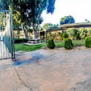 A serene garden area featuring a gate, neatly trimmed bushes, and a pathway.