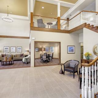 A spacious lobby with seating areas, artwork, and a staircase leading to an upper level.