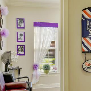 A cozy barbershop interior with purple accents, featuring a salon chair and decorative wall art.