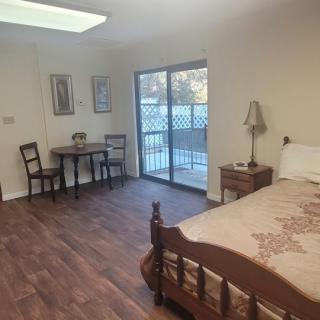 A cozy bedroom featuring a wooden bed and furniture, with a sliding glass door leading outside.