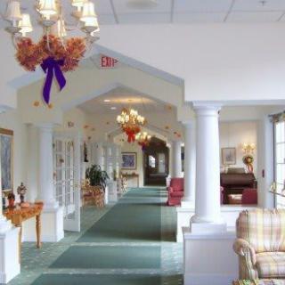 A well-decorated hallway with chandeliers, columns, and comfortable furniture.