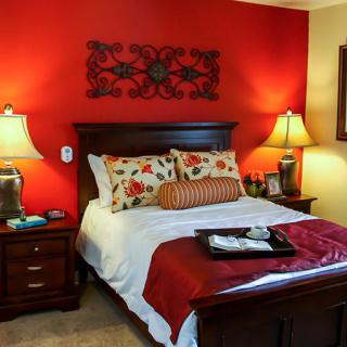 A cozy bedroom with red accent walls and classic decor.