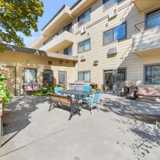 A sunny outdoor patio area at an apartment building, featuring seating and plants.