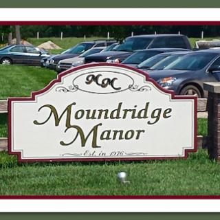 Entrance sign for Moundridge Manor with parked cars in the background.