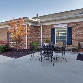 A cozy outdoor patio area with a table and chairs set against a brick house exterior.