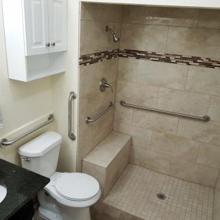 A bathroom with an accessible shower, featuring grab bars and a built-in shower seat.