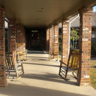 A covered porch with brick columns and wooden rocking chairs.