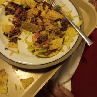 A plate of nachos with toppings including beans and lettuce on a tray.