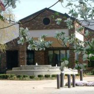 A picturesque view of a building with a fountain surrounded by trees.