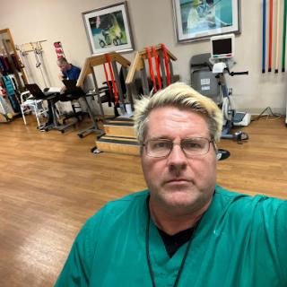 A healthcare professional in a therapy clinic, surrounded by rehabilitation equipment.