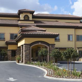 A Mediterranean-style building with a landscaped entrance and tiled roof.
