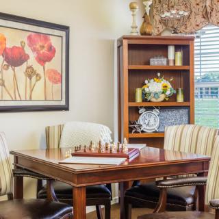 A cozy dining room with a chessboard on the table and artwork on the wall.
