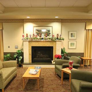 A cozy living room with green sofas and a festive fireplace decorated for the holiday season.