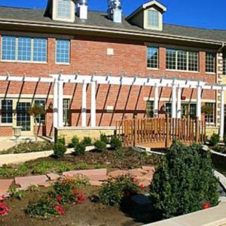 A brick building with a garden and pergola on a sunny day.